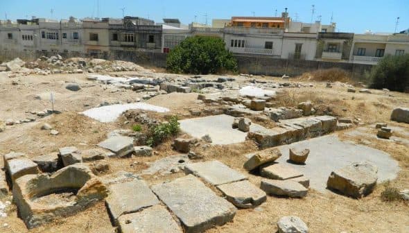 Excavated stone ruins at an archaeological site in Malta with visible structures and vegetation. - Olive Oil Times
