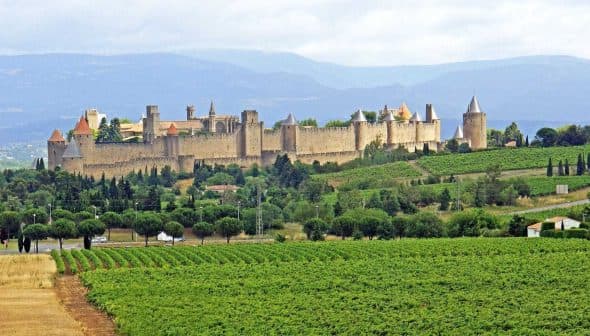 View of the medieval fortress of Carcassonne surrounded by greenery in France. - Olive Oil Times