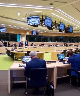 A large conference room with multiple tables and participants engaged in a meeting. - Olive Oil Times