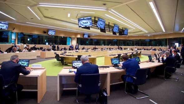 A large conference room with multiple tables and participants engaged in a meeting. - Olive Oil Times