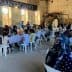 People seated at tables during a community gathering at SantEgidio with food and drinks. - Olive Oil Times