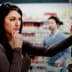 Woman with long dark hair contemplating products in a grocery store aisle while a man is in the background. - Olive Oil Times