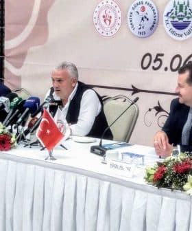 Group of officials seated at a table during a press conference with microphones and a Turkish flag. - Olive Oil Times