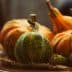 A variety of decorative pumpkins including orange and green ones arranged on a plate with natural fibers. - Olive Oil Times