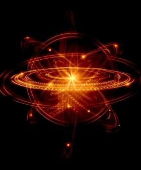 Abstract illustration of an atom with glowing rings and a central nucleus on a black background. - Olive Oil Times