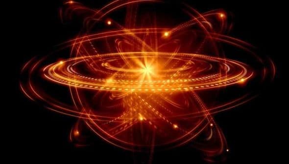 Abstract illustration of an atom with glowing rings and a central nucleus on a black background. - Olive Oil Times