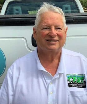 Man wearing a white shirt with a Community Emergency Response Team badge standing by a truck. - Olive Oil Times