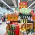 Shelves filled with different brands of cooking oils in a supermarket aisle. - Olive Oil Times