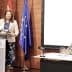 A woman presenting at a podium with flags of Spain and the European Union in the background. - Olive Oil Times