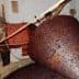 Large cone-shaped container filled with dark olive paste in a traditional olive oil production setting. - Olive Oil Times