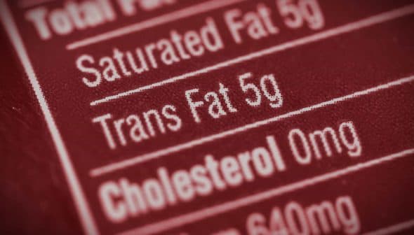 Close-up of a nutrition label indicating 5g of trans fat content. - Olive Oil Times
