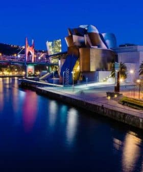 Guggenheim Museum in Bilbao illuminated at night with reflections in the water. - Olive Oil Times