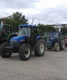 A row of agricultural tractors parked in a lot, featuring various colors and models. - Olive Oil Times