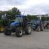 A row of agricultural tractors parked in a lot, featuring various colors and models. - Olive Oil Times