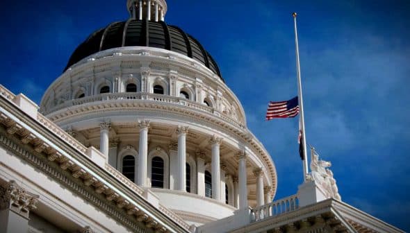 Close-up view of the California State Capitol building with a flag at half-mast. - Olive Oil Times