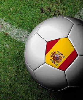 A soccer ball featuring the Spanish flag design on a grass field. - Olive Oil Times