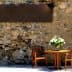 A wooden table with two chairs and a vase of flowers on a stone wall background. - Olive Oil Times