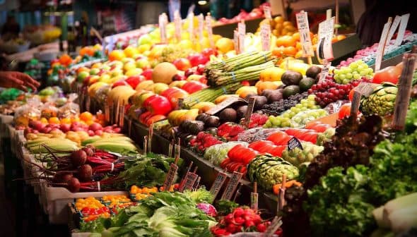 Colorful display of fresh fruits and vegetables arranged at a market stall. - Olive Oil Times