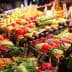 Colorful display of fresh fruits and vegetables arranged at a market stall. - Olive Oil Times