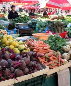 Display of fresh vegetables and fruits including beets, carrots, and lemons at a market stall. - Olive Oil Times
