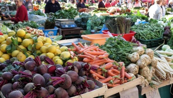 Display of fresh vegetables and fruits including beets, carrots, and lemons at a market stall. - Olive Oil Times