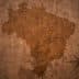 Silhouette map of Brazil displayed on a textured, cracked brown background. - Olive Oil Times