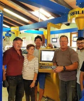Six individuals standing in an olive oil production facility near machinery and equipment. - Olive Oil Times