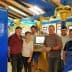 Six individuals standing in an olive oil production facility near machinery and equipment. - Olive Oil Times
