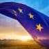 European Union flag with stars waving against a sunset sky with clouds. - Olive Oil Times