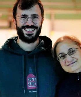 A man and a woman smiling while standing close to each other in a well-lit indoor setting. - Olive Oil Times