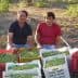 Two men sitting beside baskets filled with freshly harvested olives in a field. - Olive Oil Times