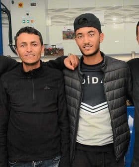 Four men wearing black clothing posing together in a casual setting. - Olive Oil Times