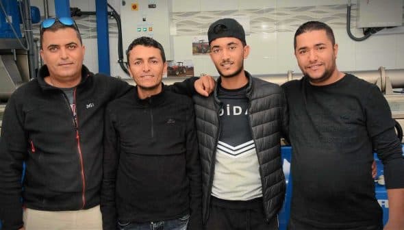 Four men wearing black clothing posing together in a casual setting. - Olive Oil Times