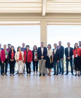 A group of individuals posing for a photo at an event, standing together in a spacious indoor area. - Olive Oil Times