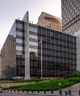 Contemporary office building featuring a glass facade and surrounding greenery in an urban setting. - Olive Oil Times