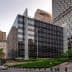 Contemporary office building featuring a glass facade and surrounding greenery in an urban setting. - Olive Oil Times