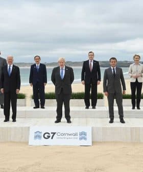Group photo of G7 leaders standing on a stage at a beach in Cornwall. - Olive Oil Times