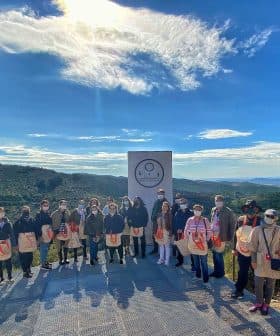A group of individuals standing together outdoors, wearing bags and posing for a photo in a natural setting. - Olive Oil Times