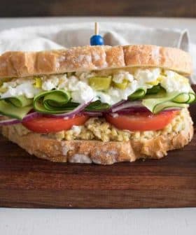 A sandwich made with whole grain bread, filled with egg salad, cucumbers, tomatoes, and pickles. - Olive Oil Times