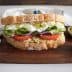 A sandwich made with whole grain bread, filled with egg salad, cucumbers, tomatoes, and pickles. - Olive Oil Times