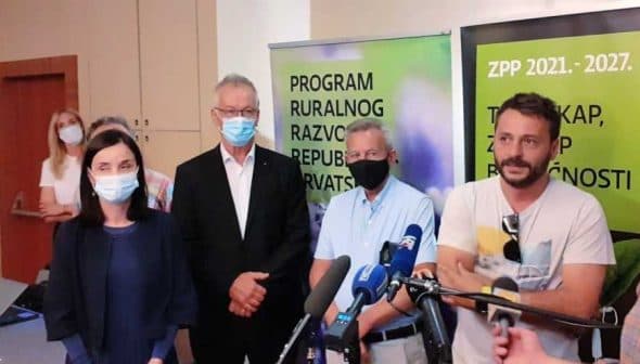 A group of four individuals standing together at a press conference, wearing masks and formal attire. - Olive Oil Times