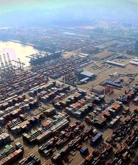 Aerial view of a busy container port with numerous shipping containers stacked. - Olive Oil Times