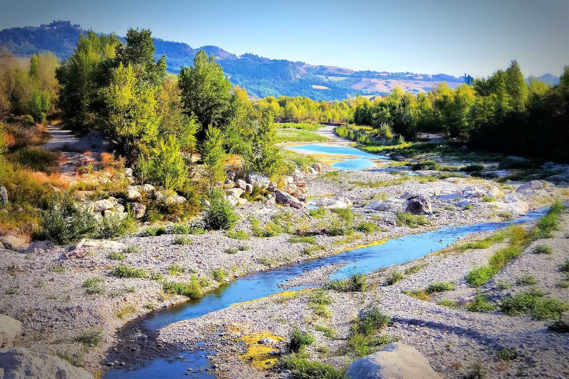 A river winding through a landscape with trees and rocky areas under a clear sky. - Olive Oil Times
