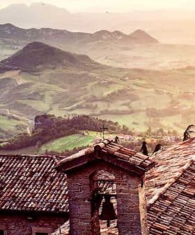 View of rooftops with a mountainous landscape in the background during sunset. - Olive Oil Times