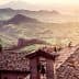 View of rooftops with a mountainous landscape in the background during sunset. - Olive Oil Times