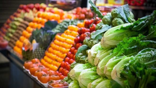 A colorful display of fresh vegetables and fruits including lettuce, tomatoes, and peppers at a market. - Olive Oil Times