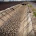Cracked dry irrigation canal running alongside a gravel road in an agricultural area. - Olive Oil Times