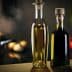 Two glass bottles containing olive oil, one with a light golden liquid and the other with a dark liquid, placed on a wooden surface. - Olive Oil Times