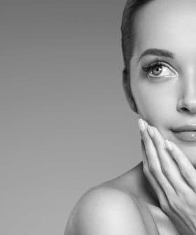 Black and white portrait of a woman with smooth skin and a thoughtful expression, gently touching her face. - Olive Oil Times