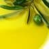 A close-up image of olive oil in a bowl with an olive branch and olives resting on the surface. - Olive Oil Times
